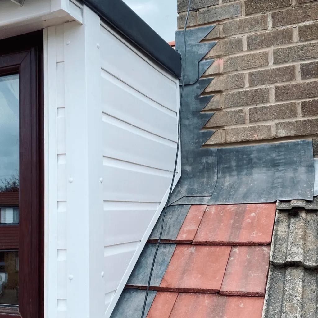 Brick chimney stack with new lead flashing repair on tiled roof
