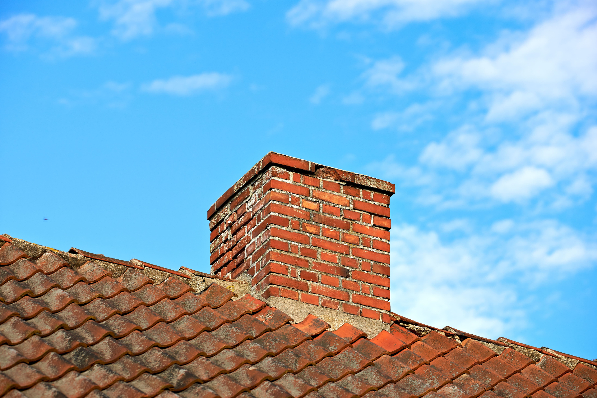 Brick chimney stack with new lead flashing repair on tiled roof