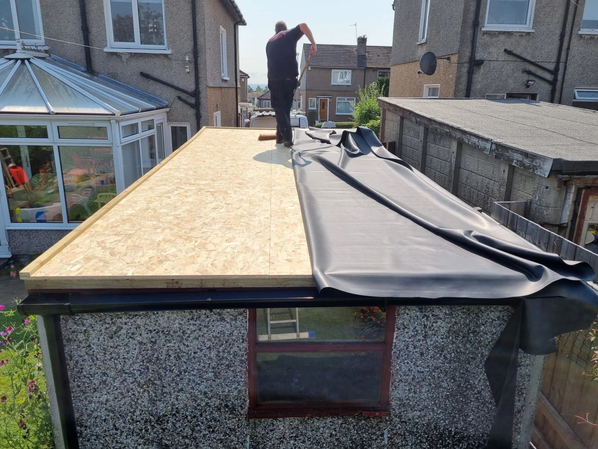 EPDM rubber membrane being rolled out on flat roof extension